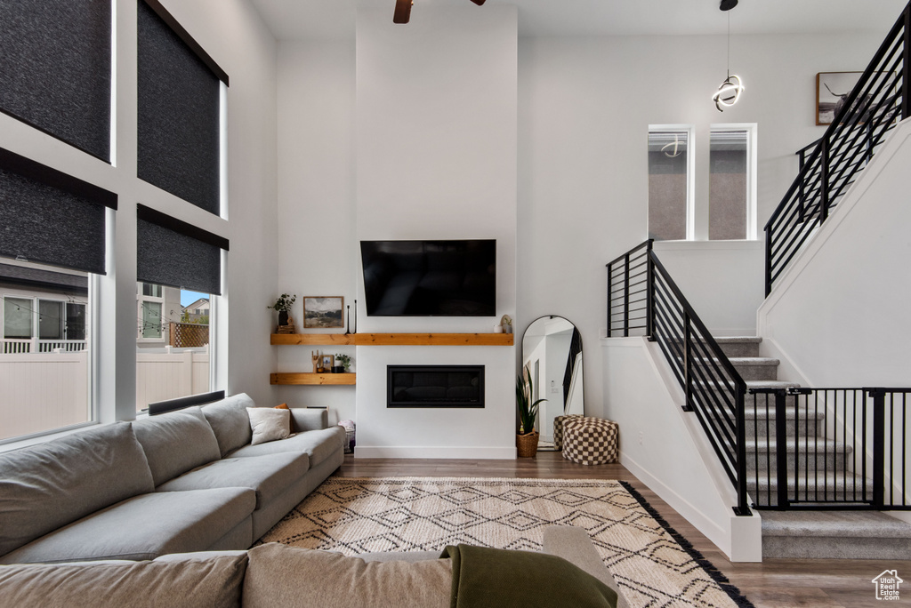 Living room with a towering ceiling, hardwood / wood-style flooring, and ceiling fan