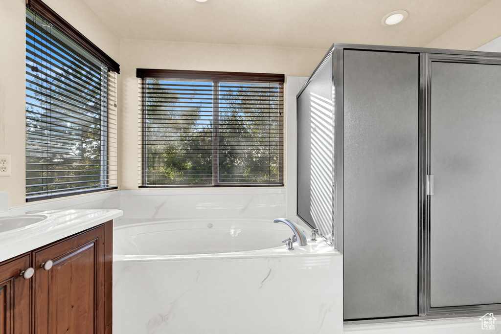 Bathroom featuring independent shower and bath, a wealth of natural light, and vanity