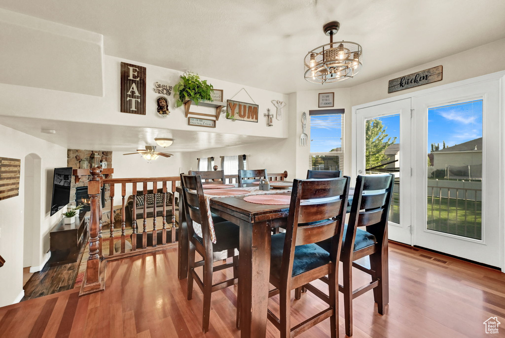 Dining space with ceiling fan with notable chandelier and hardwood / wood-style flooring