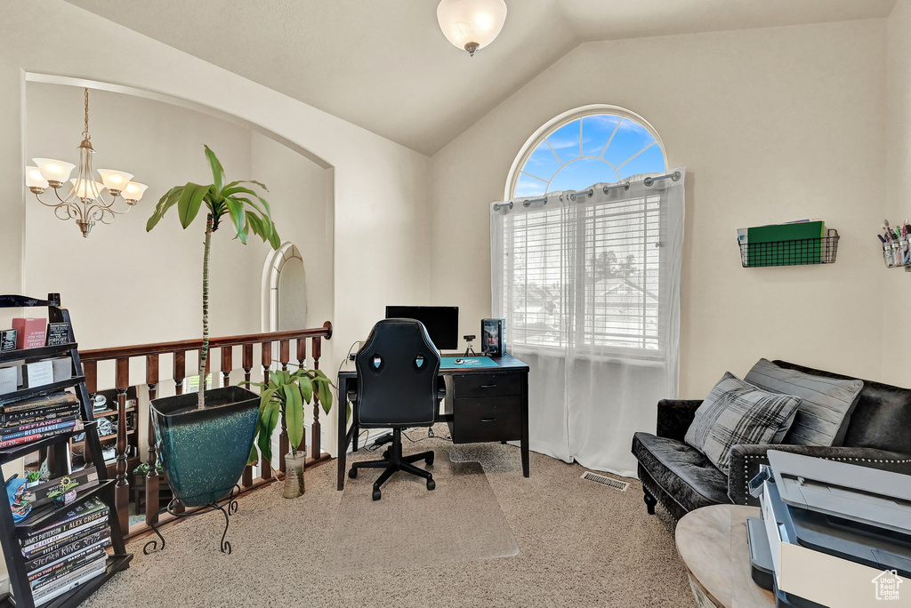 Office with vaulted ceiling, an inviting chandelier, and light colored carpet