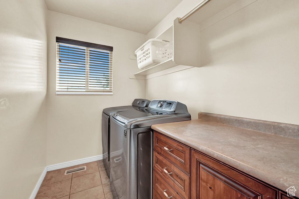 Washroom with washing machine and dryer and light tile patterned floors