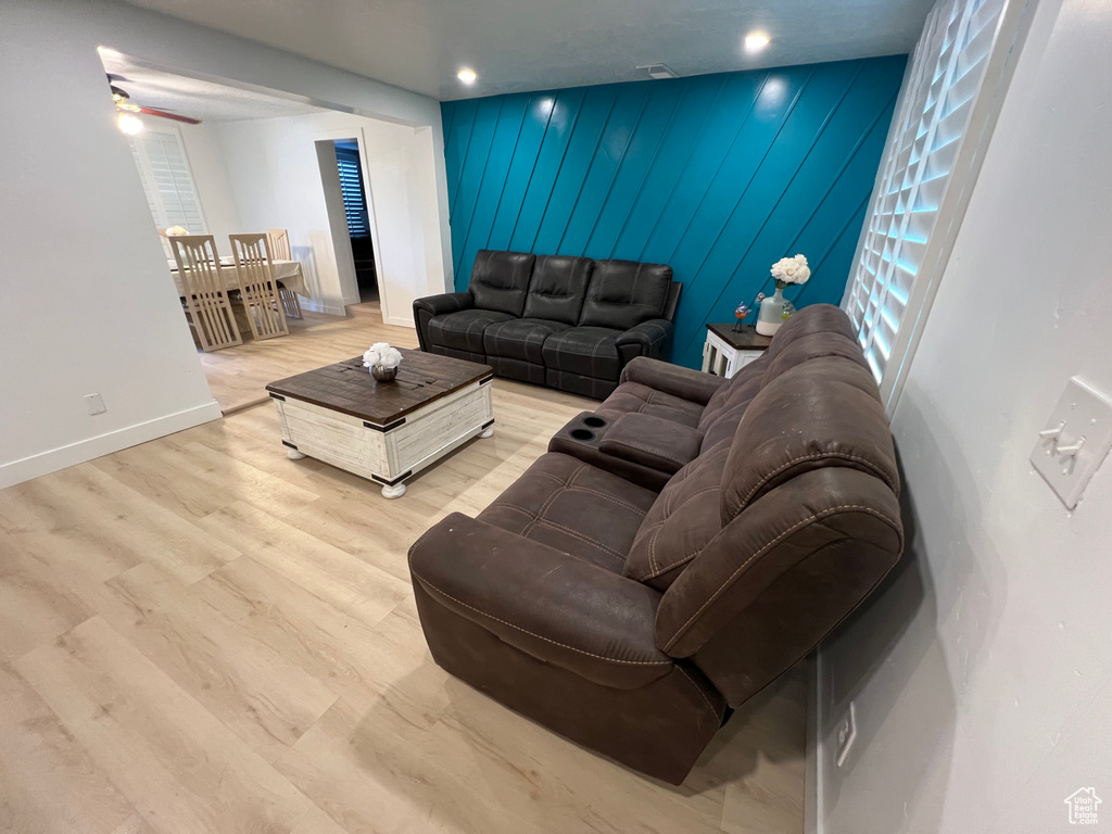 Living room with ceiling fan, wood walls, and light hardwood / wood-style floors