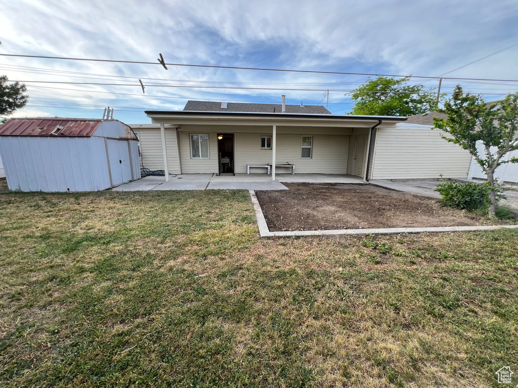 Back of house with a storage shed, a yard, and a patio area