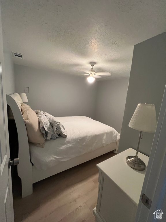 Bedroom featuring a textured ceiling, light hardwood / wood-style flooring, and ceiling fan