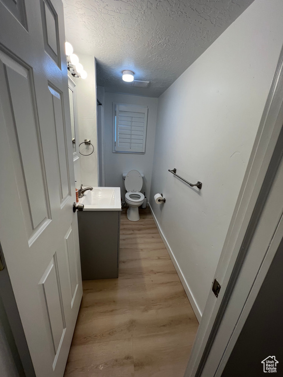 Bathroom featuring vanity, toilet, hardwood / wood-style floors, and a textured ceiling