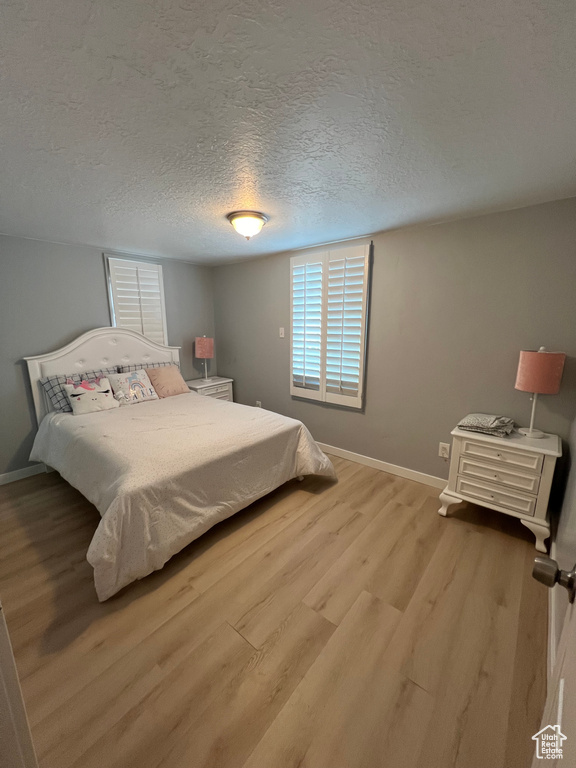 Bedroom featuring a textured ceiling and light hardwood / wood-style floors