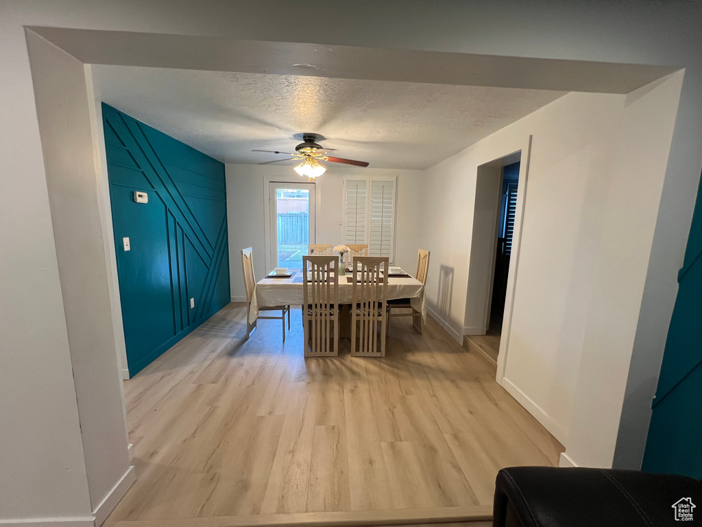 Dining space featuring a textured ceiling, ceiling fan, and light wood-type flooring