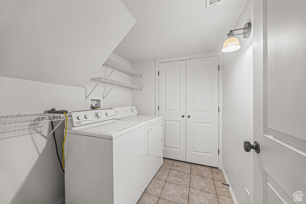 Laundry room with light tile patterned floors and washing machine and dryer