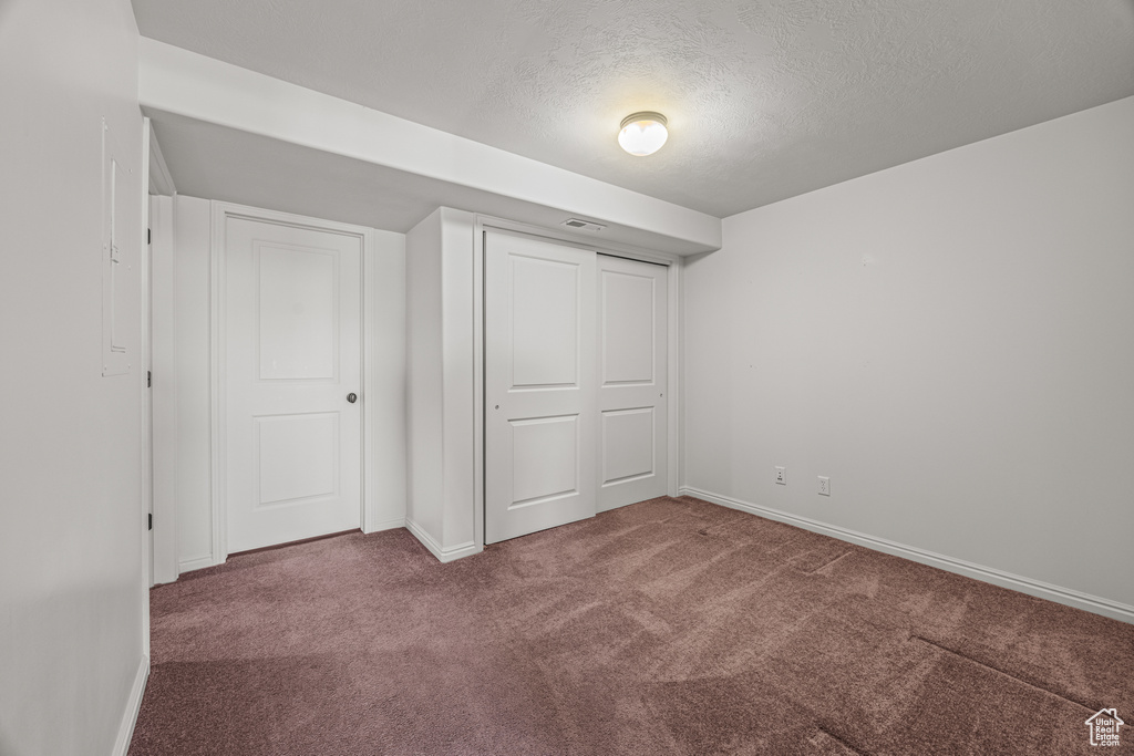 Unfurnished bedroom featuring a textured ceiling, carpet, and a closet