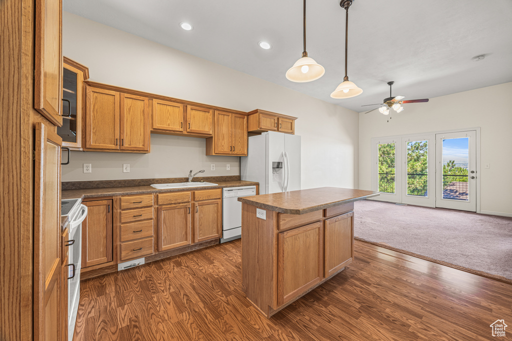 Kitchen with white appliances, a kitchen island, sink, ceiling fan, and dark hardwood / wood-style floors