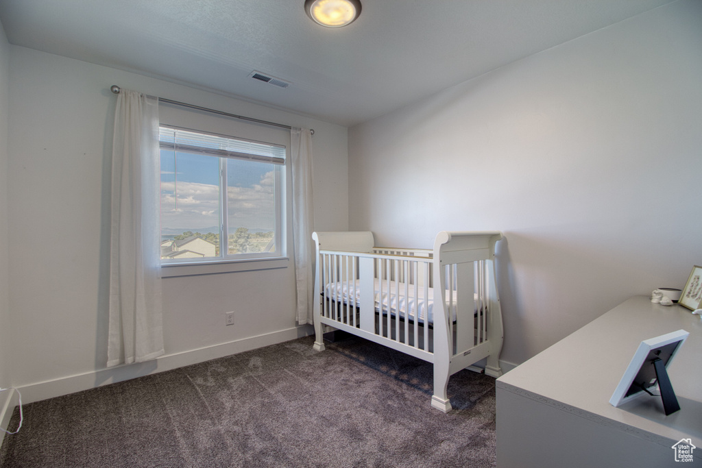 Bedroom with dark colored carpet and a crib