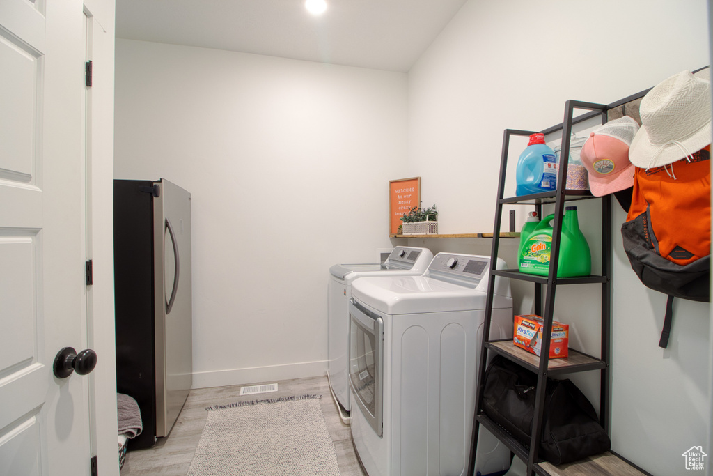 Washroom with light wood-type flooring and independent washer and dryer