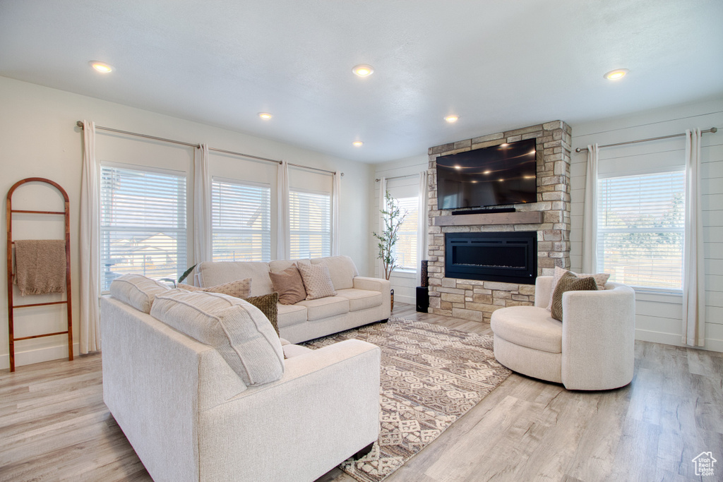 Living room featuring plenty of natural light, light hardwood / wood-style flooring, and a stone fireplace