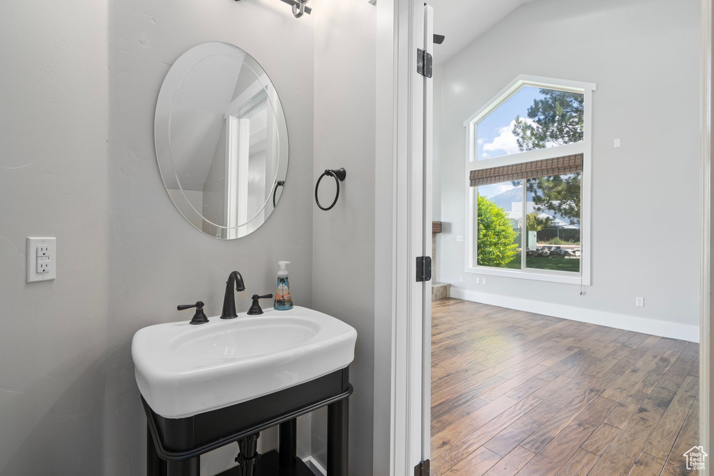 Bathroom featuring vaulted ceiling, sink, and hardwood / wood-style flooring