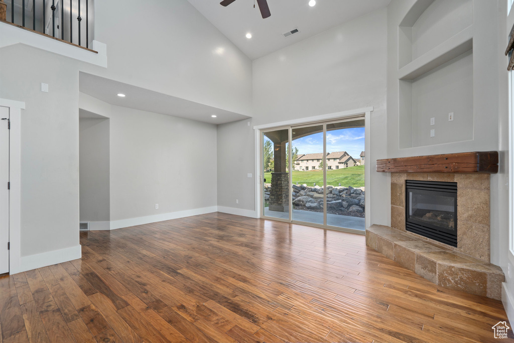 Unfurnished living room featuring a fireplace, high vaulted ceiling, hardwood / wood-style floors, and ceiling fan