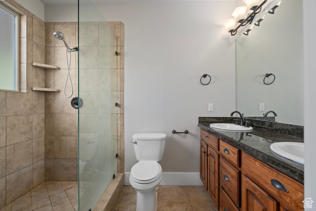 Bathroom with vanity, toilet, tiled shower, and tile patterned floors