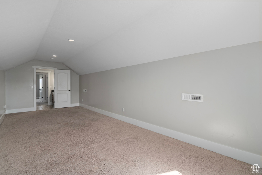 Bonus room with light carpet and vaulted ceiling