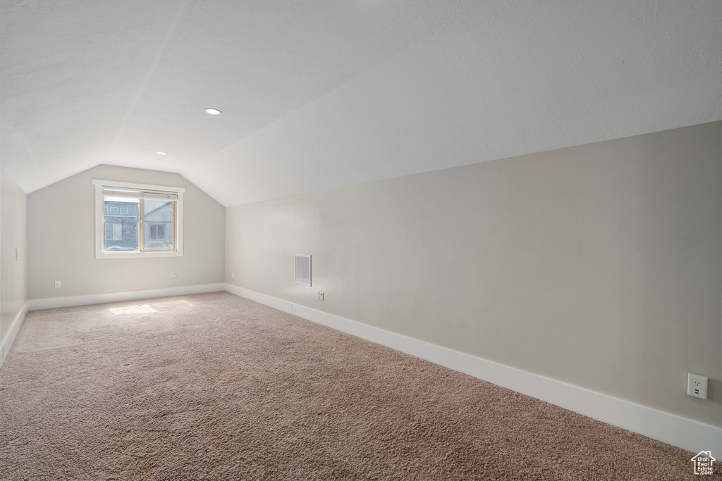 Additional living space featuring vaulted ceiling and carpet floors