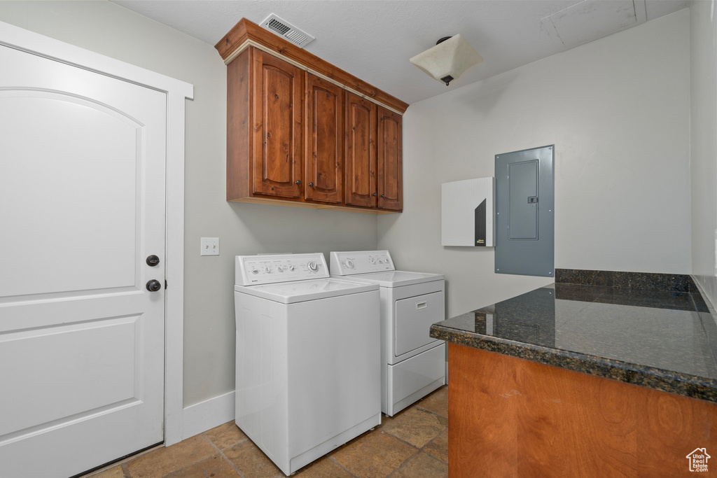 Washroom featuring electric panel, cabinets, and washer and clothes dryer