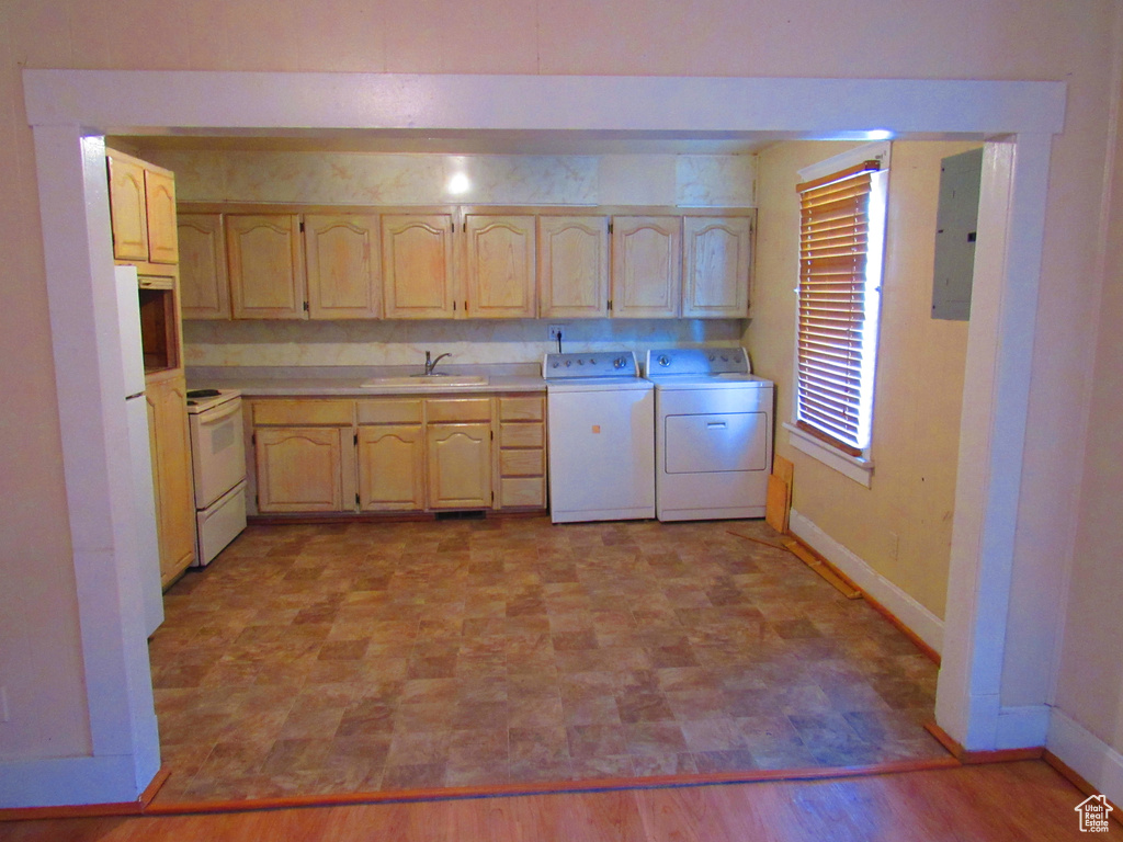 Kitchen with light brown cabinetry, independent washer and dryer, light hardwood / wood-style floors, sink, and white electric stove