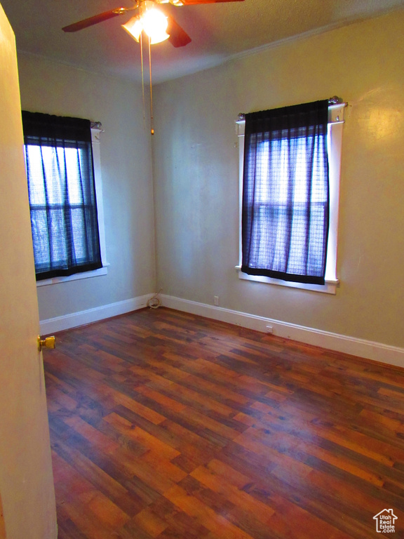 Empty room with dark wood-type flooring and ceiling fan