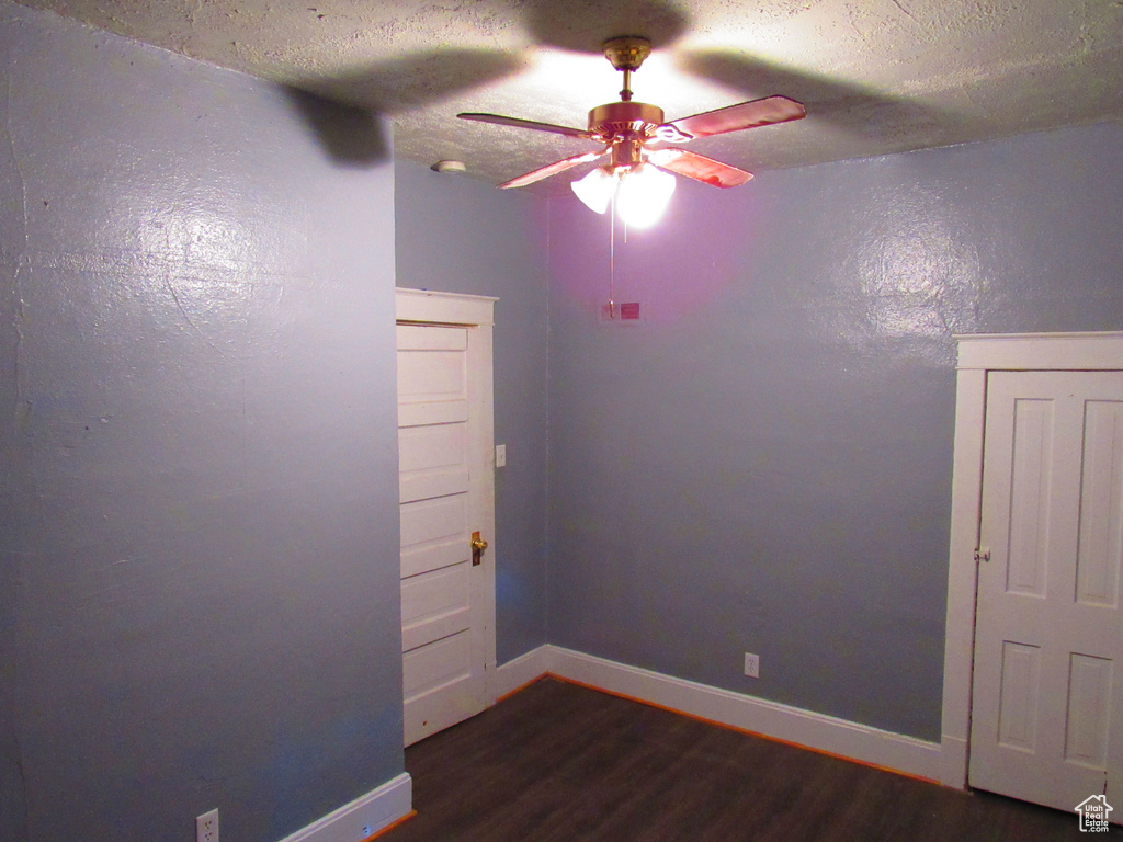 Unfurnished room with a textured ceiling, ceiling fan, and dark hardwood / wood-style floors