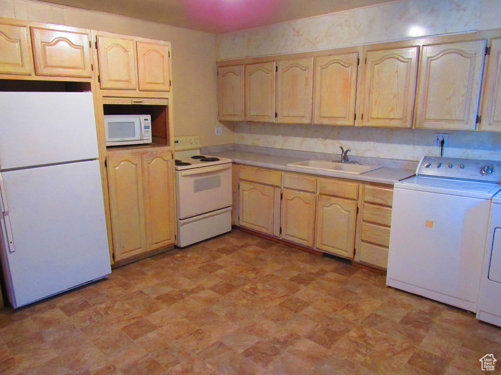 Kitchen with white appliances, light brown cabinets, and sink