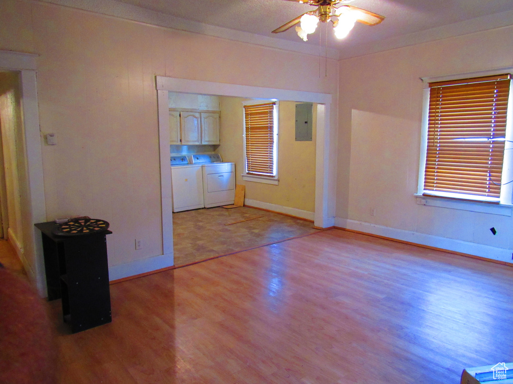 Unfurnished room featuring ceiling fan, electric panel, light hardwood / wood-style floors, and independent washer and dryer