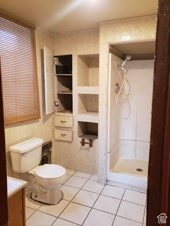 Bathroom with tile walls, toilet, vanity, and tile patterned flooring