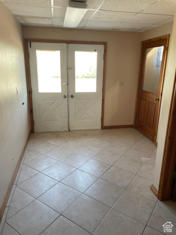 Doorway with a drop ceiling, french doors, and light tile patterned floors