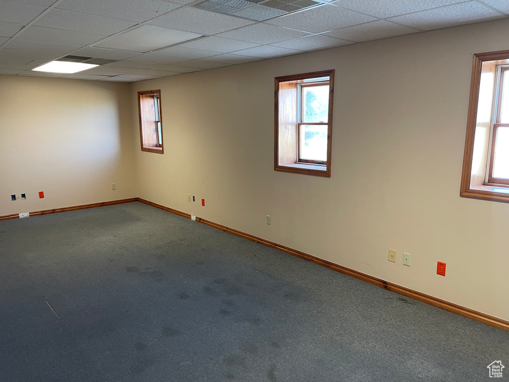 Carpeted spare room featuring a drop ceiling