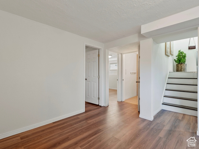 Spare room featuring a textured ceiling and dark wood-type flooring