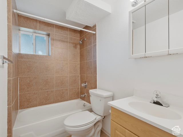 Full bathroom with vanity, tiled shower / bath combo, and toilet