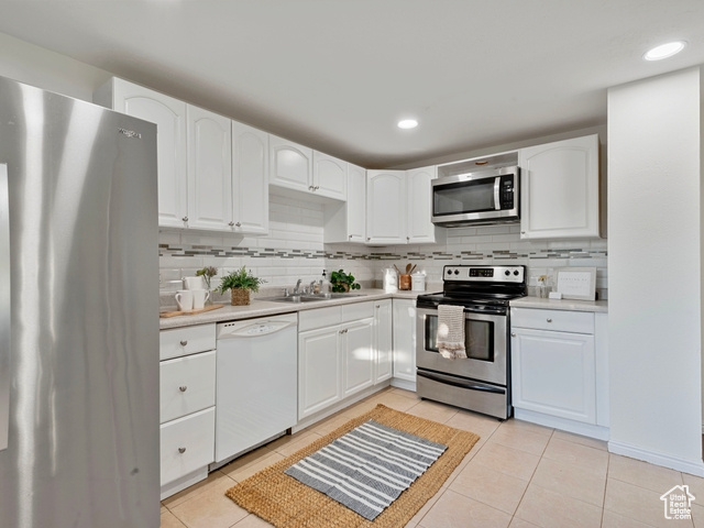 Kitchen featuring stainless steel appliances, backsplash, and white cabinetry