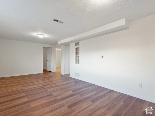 Unfurnished room featuring a textured ceiling and dark hardwood / wood-style floors