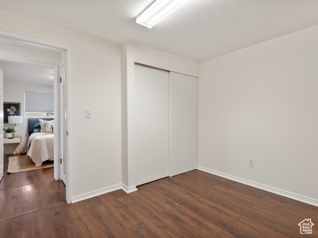 Unfurnished bedroom featuring a closet and dark hardwood / wood-style flooring