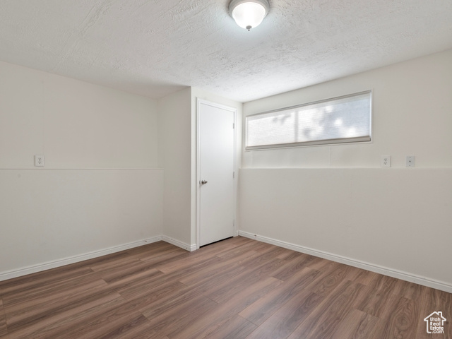 Unfurnished room with a textured ceiling and dark wood-type flooring