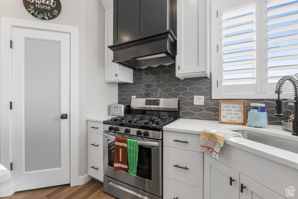 Kitchen featuring gas range, dark hardwood / wood-style floors, light stone countertops, sink, and white cabinets