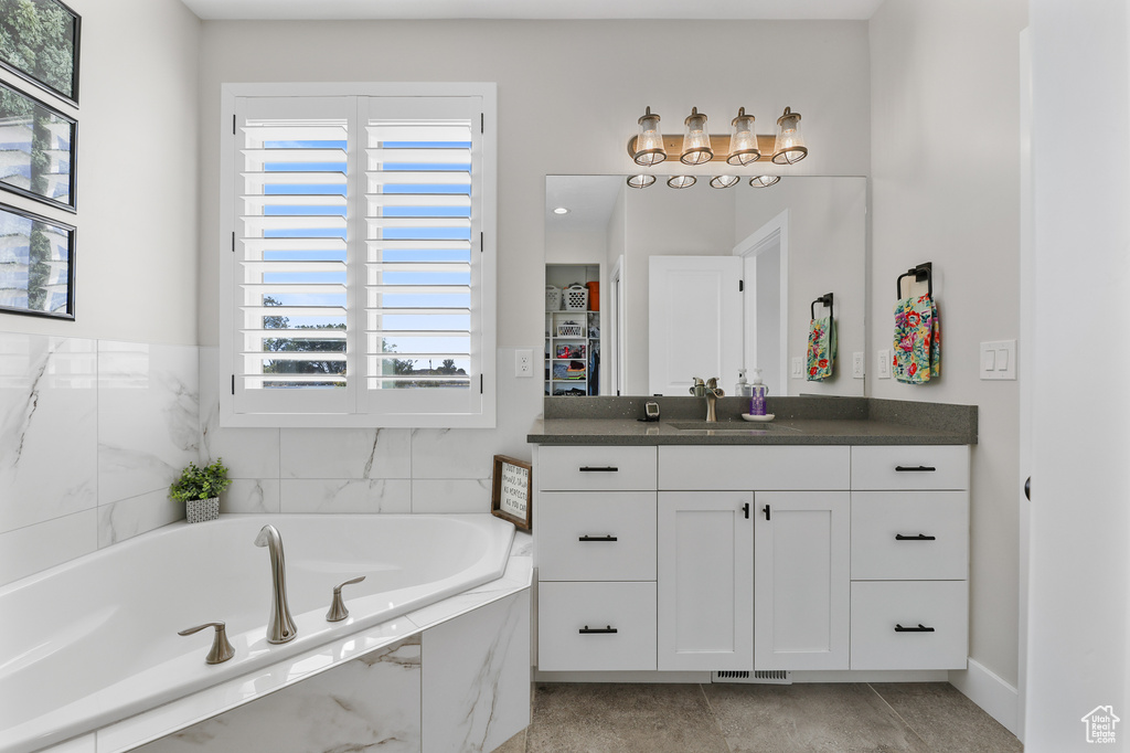 Bathroom featuring tiled tub and vanity