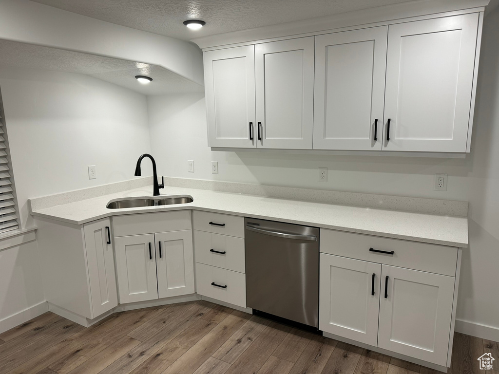 Kitchen featuring dishwasher, white cabinetry, sink, and light hardwood / wood-style floors