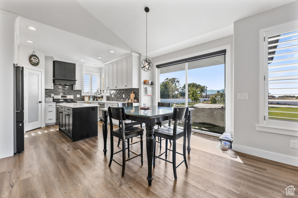 Dining room with hardwood / wood-style floors, vaulted ceiling, and sink