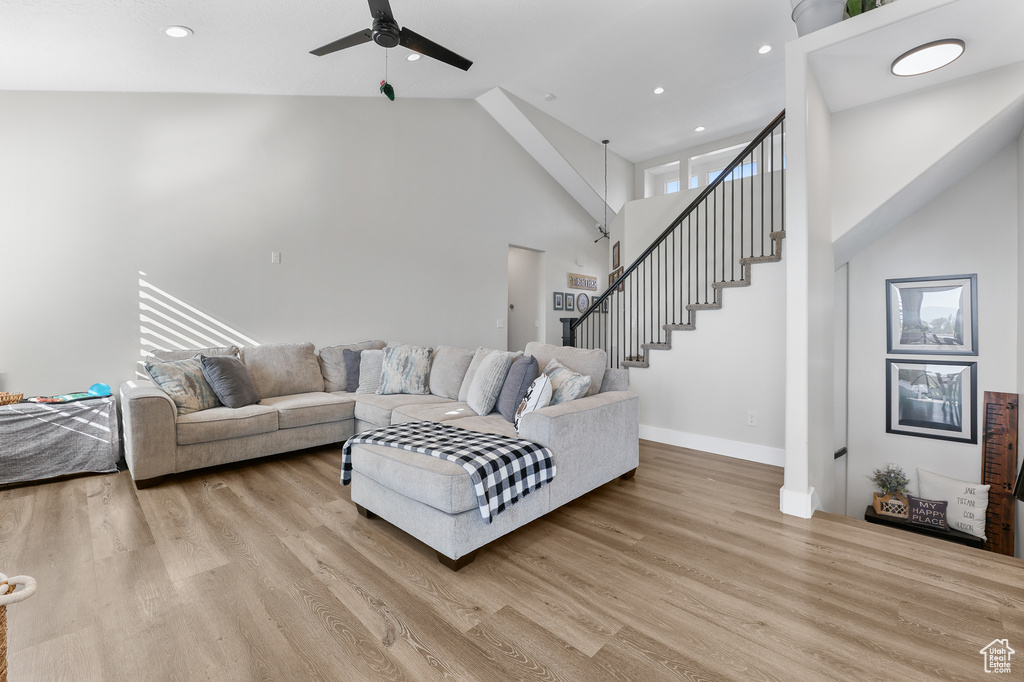 Living room featuring high vaulted ceiling, ceiling fan, and light hardwood / wood-style floors