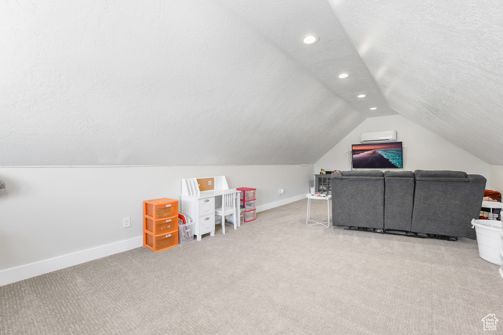 Playroom featuring light colored carpet, a textured ceiling, and vaulted ceiling