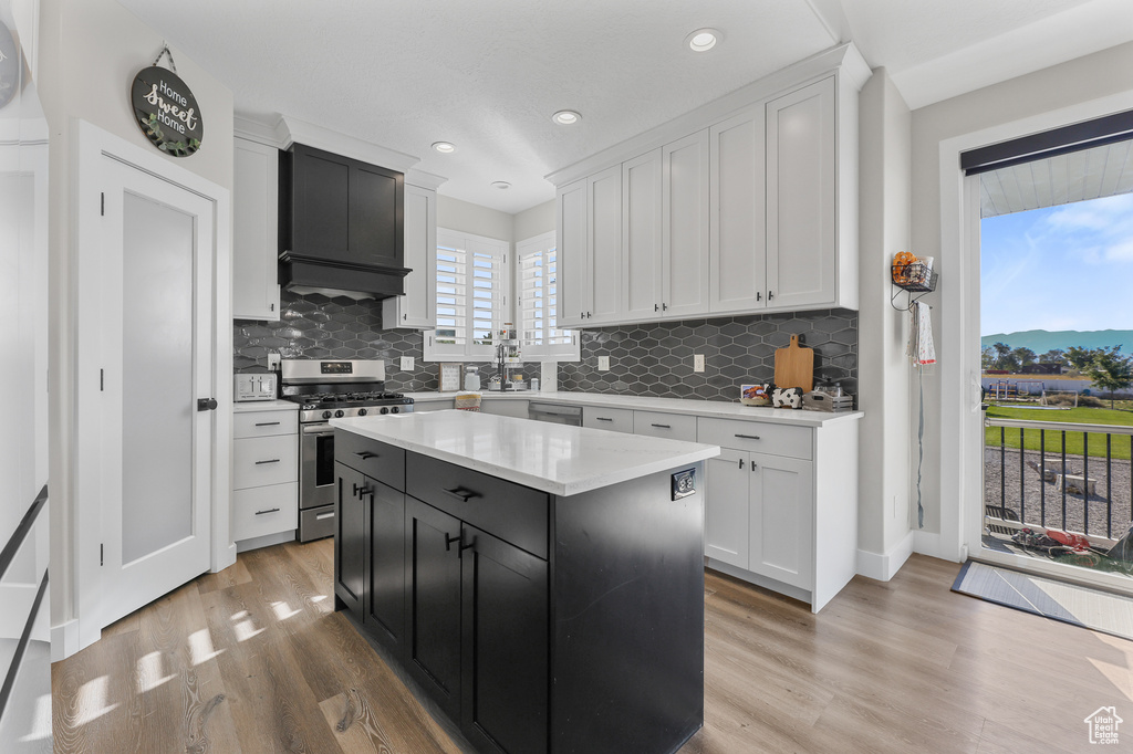 Kitchen featuring white cabinets, premium range hood, gas stove, and a center island