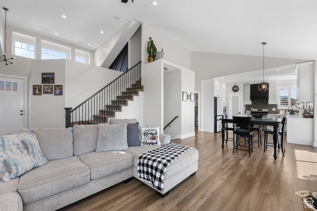 Living room with a healthy amount of sunlight, sink, light hardwood / wood-style flooring, and high vaulted ceiling