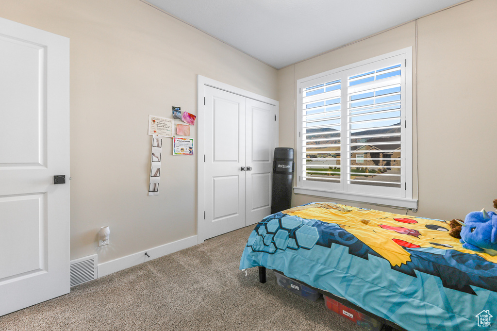 Bedroom with multiple windows, a closet, and carpet floors