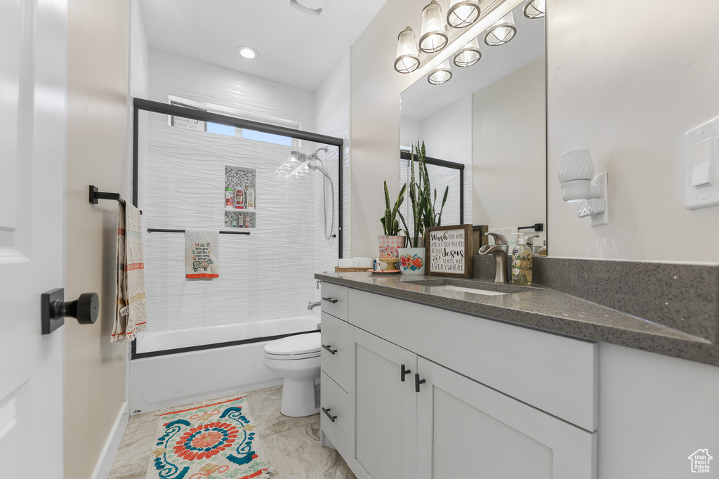 Full bathroom with combined bath / shower with glass door, vanity, and toilet