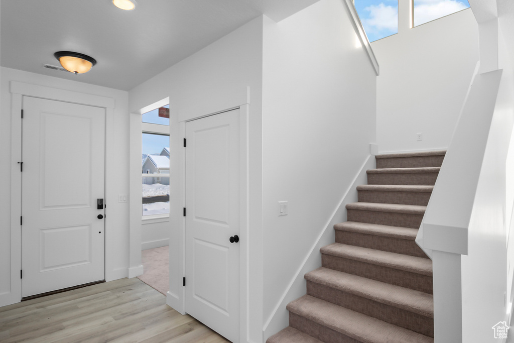 Stairs featuring plenty of natural light and hardwood / wood-style flooring