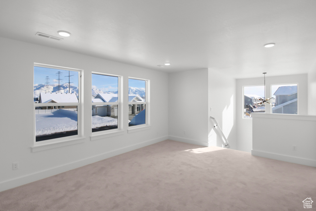 Carpeted empty room with an inviting chandelier