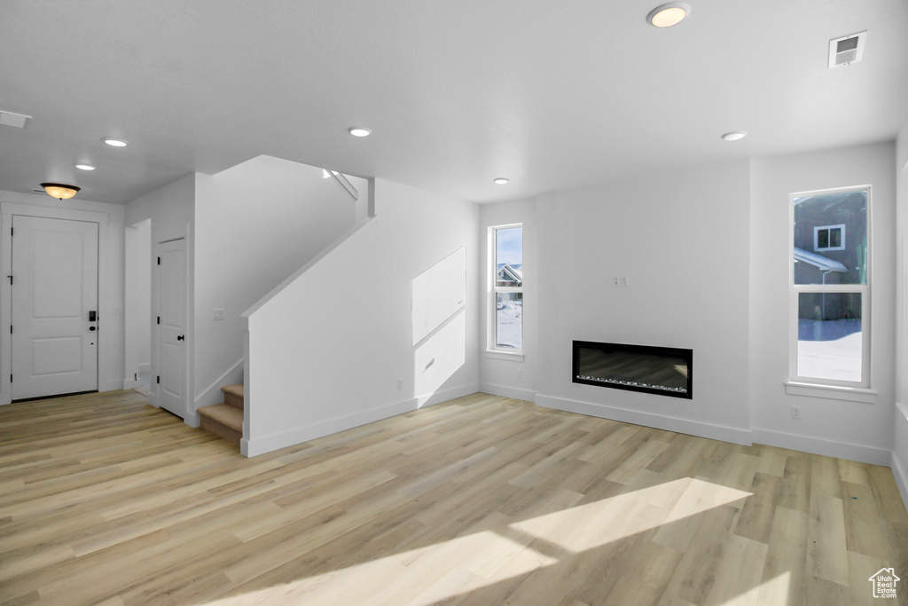 Unfurnished living room featuring a wealth of natural light and light hardwood / wood-style flooring